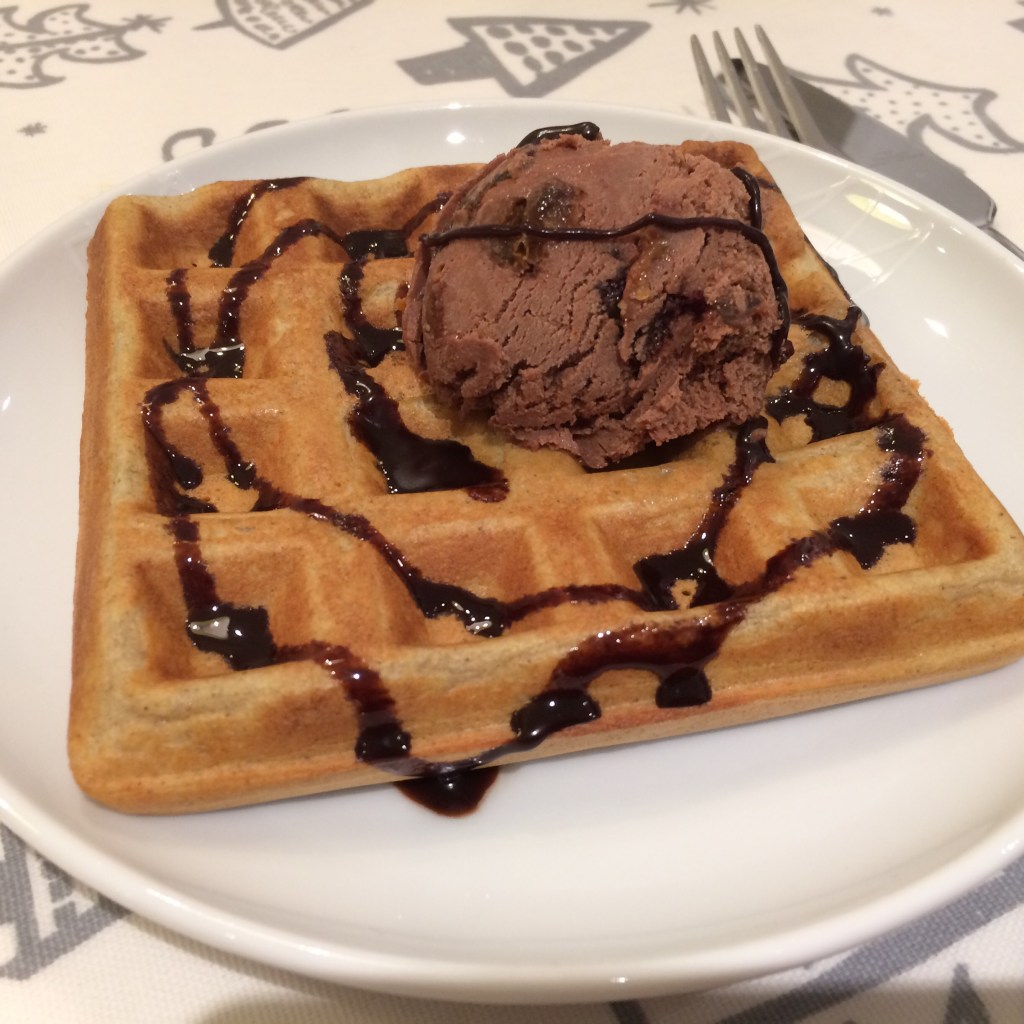 a home made waffle with chocolate ice cream and chocolate sauce, sitting on a white plate