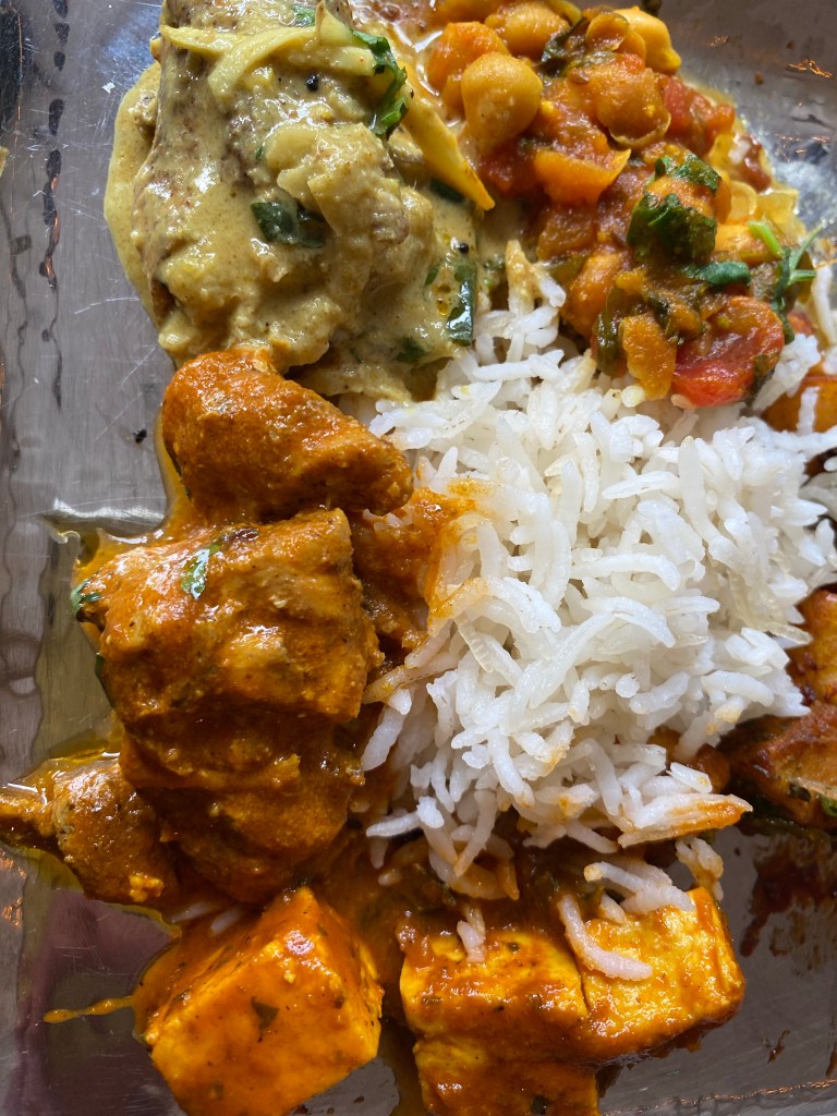 An assortment of Indian curry with rice on a metal plate