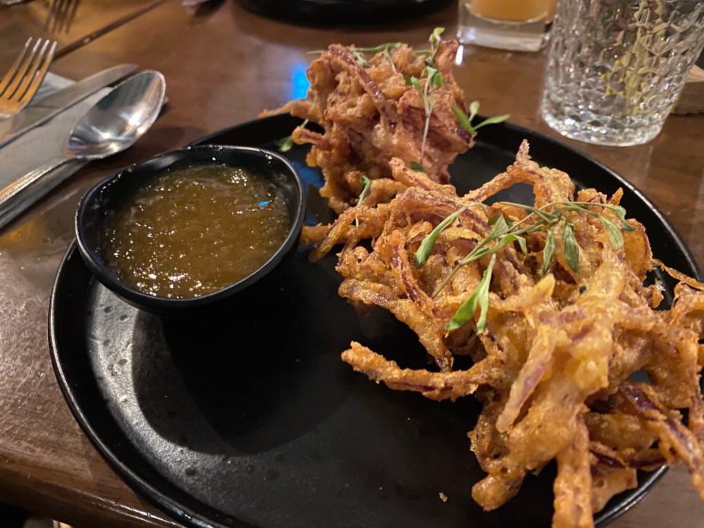 a plate with two mahoosive onion bhajis and a big bowl of mango chutney
