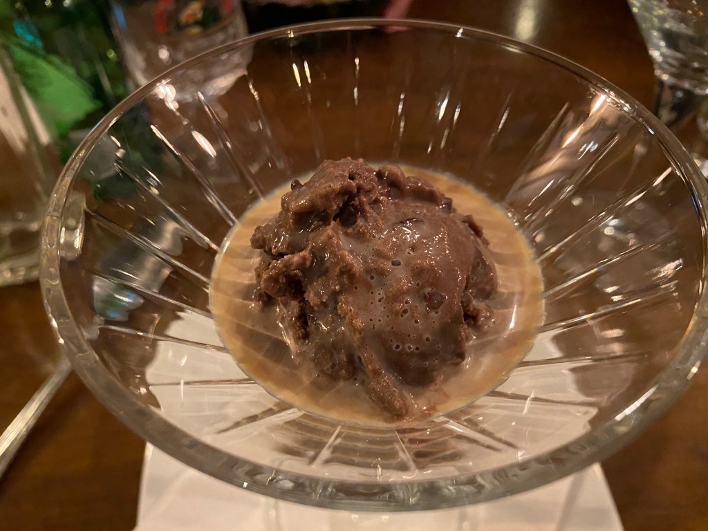a glass containing chocolate ice cream with a shot of Baileys poured on top