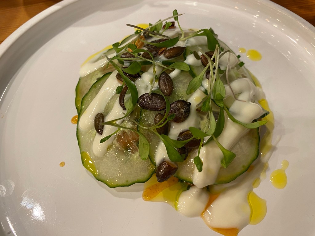 A starter portion of curry cured salmon hiding underneath some cucumber, drizzled with mint sauce and mango chutney 