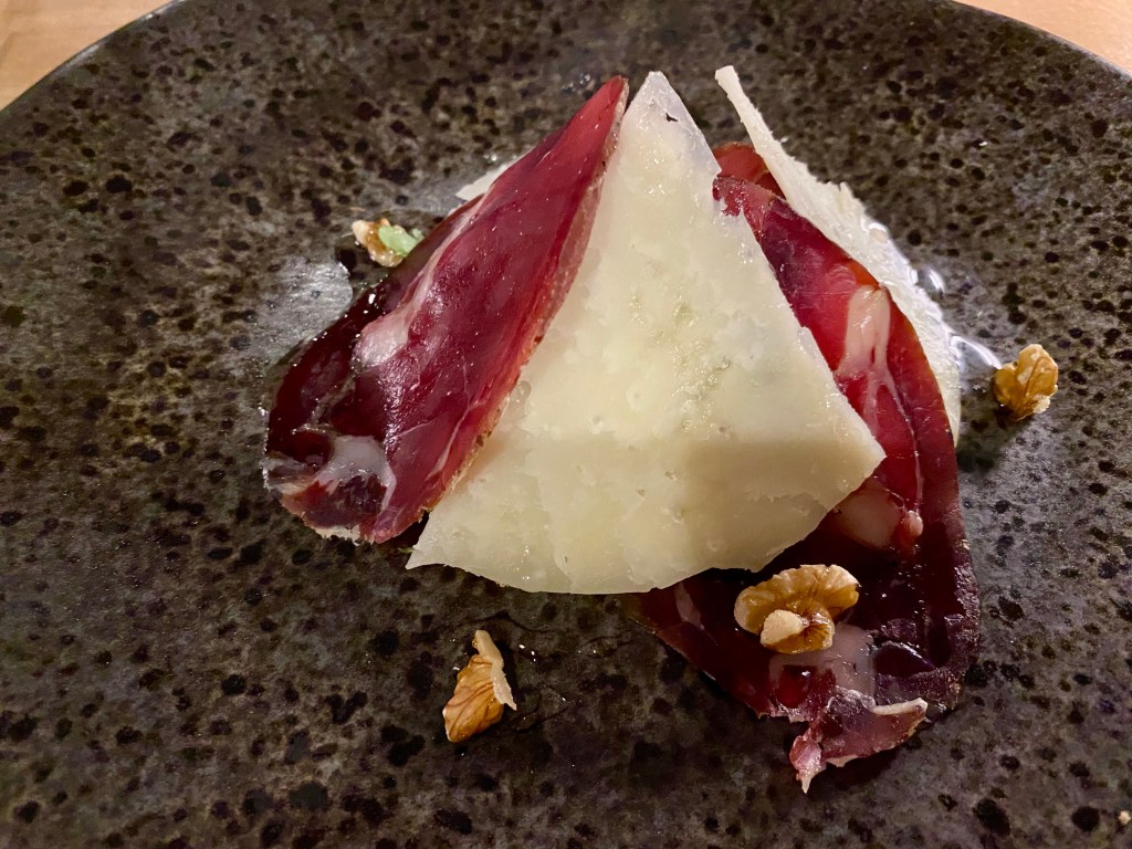 plate with a starter portion of wild boar ham with truffle honey, walnuts and pecorino cheese