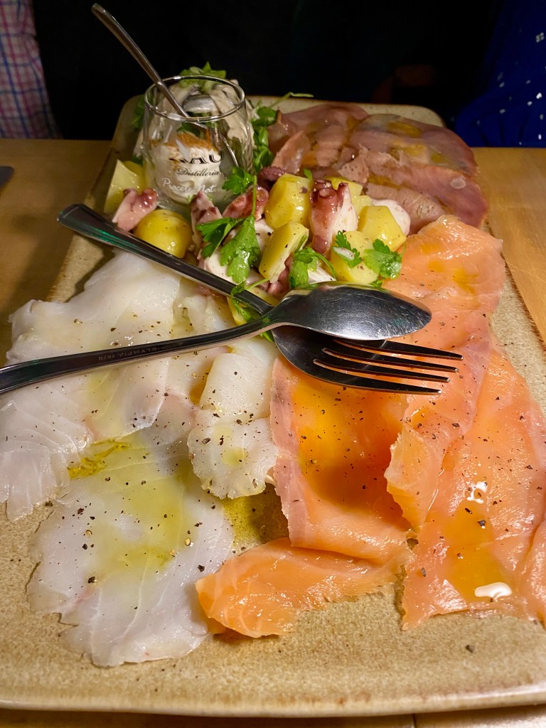 a fish sharing platter with thin slices of tuna, cod and salmon, and an octopus salad