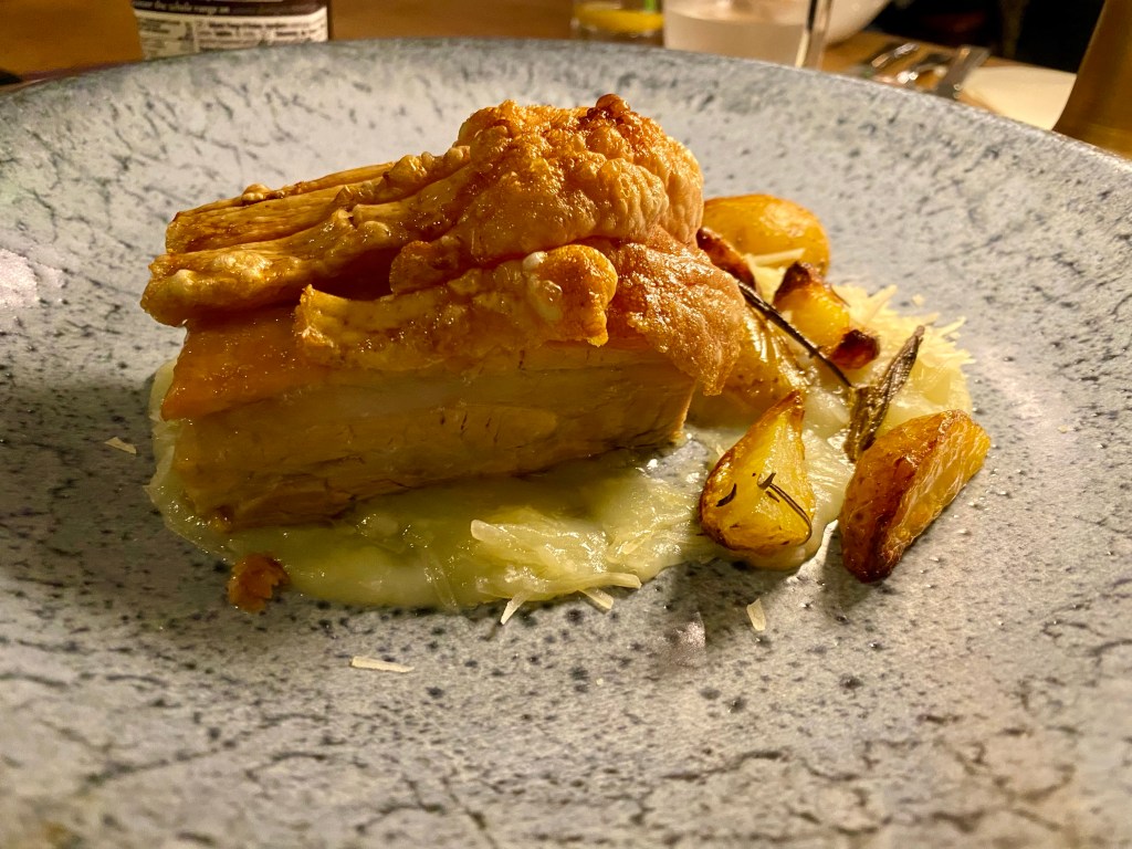 belly pork and roast potatoes and a plate