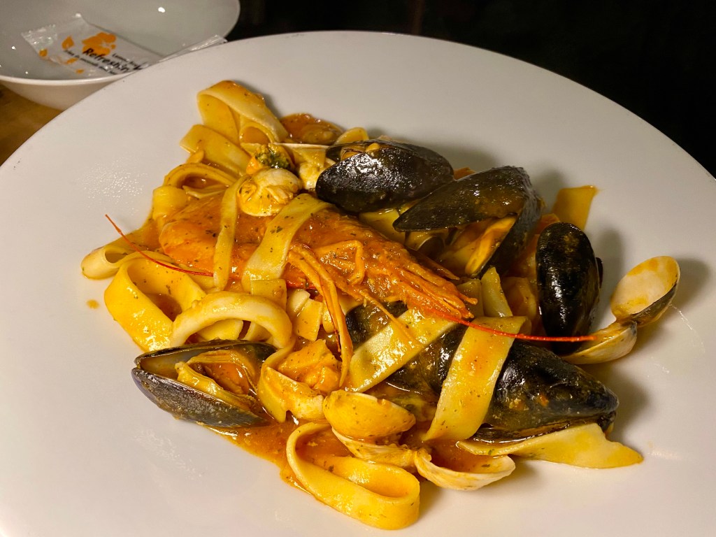bowl of parpadelle pasta strips with prawns and mussels