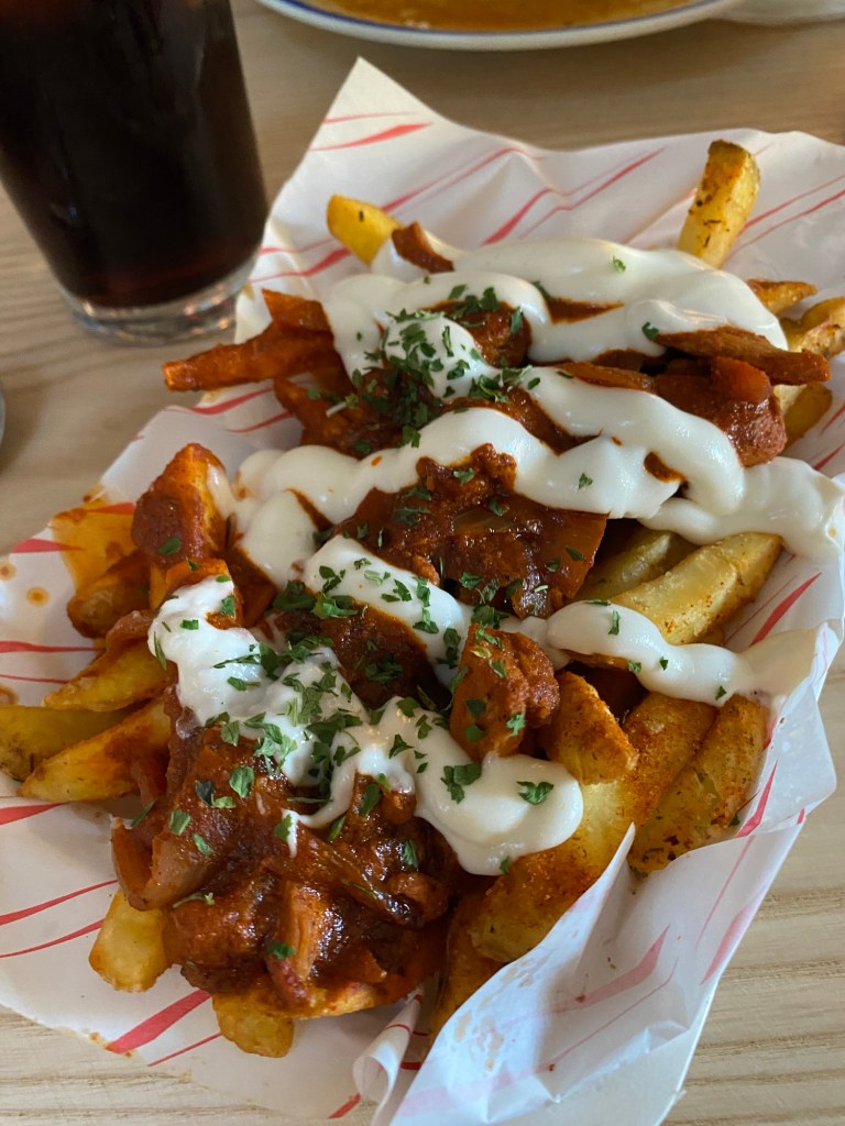 loaded chips on a piece of paper on a table with a glass of Coca Cola