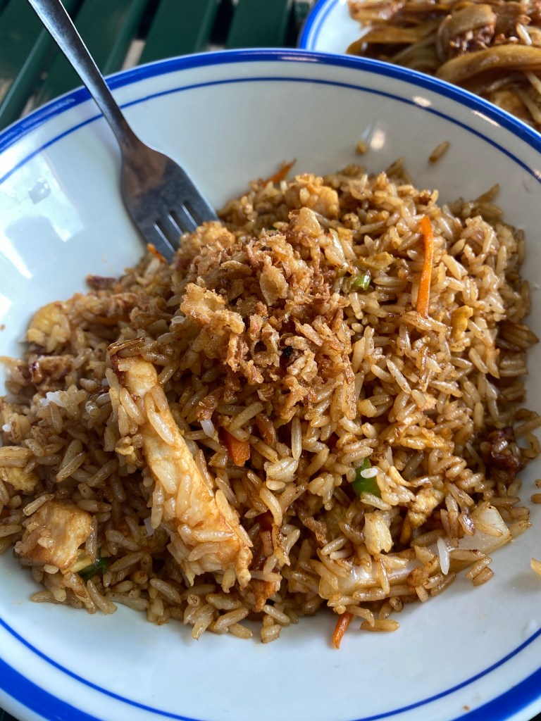 Chicken and rice (nasi goreng) in a white bowl with a blue rim