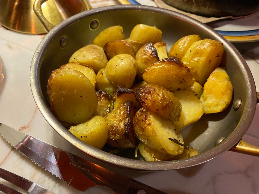 A metal dish containing roasted baby potatoes with rosemary