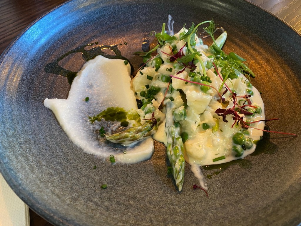 A grey plate containing a delicately placed splodge of cauliflower puree, asparagus and peas in a white sauce, and some micro herbs as a garnish. There were flakes of cod cheek in the mix, if you looked quite hard. 